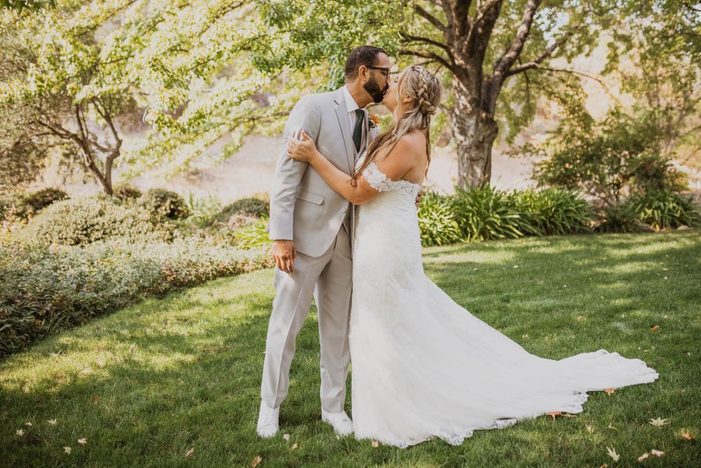 Couple shares intimate first look moment in sunny outdoor garden setting.