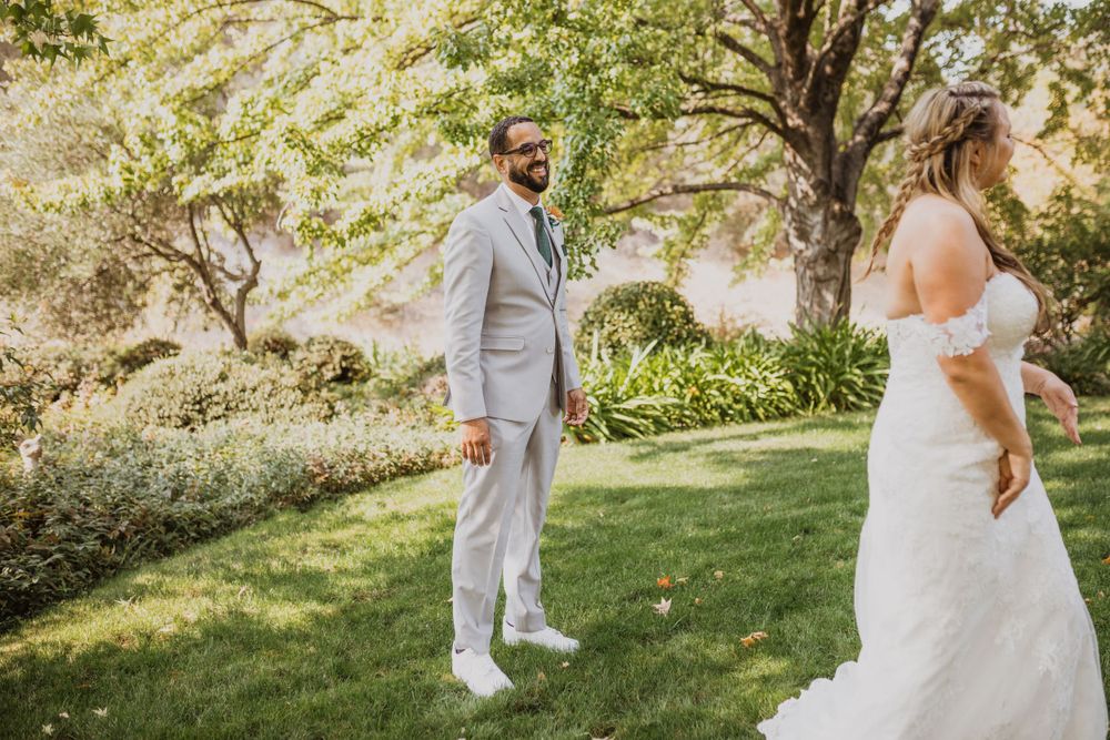 A couple in wedding attire share a tender moment in a sunlit garden setting.