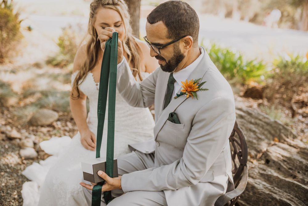 A couple shares an intimate moment while sitting outdoors during their wedding.