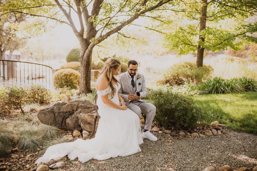 Couple in wedding attire sharing a quiet moment in a garden setting.
