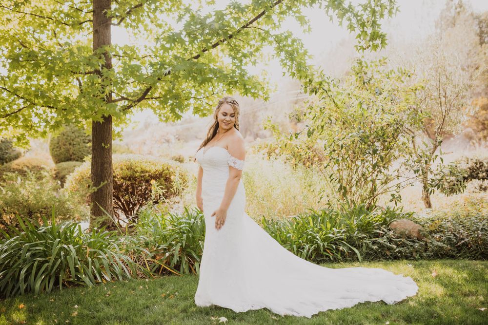 White wedding dress flows elegantly against lush garden landscape.