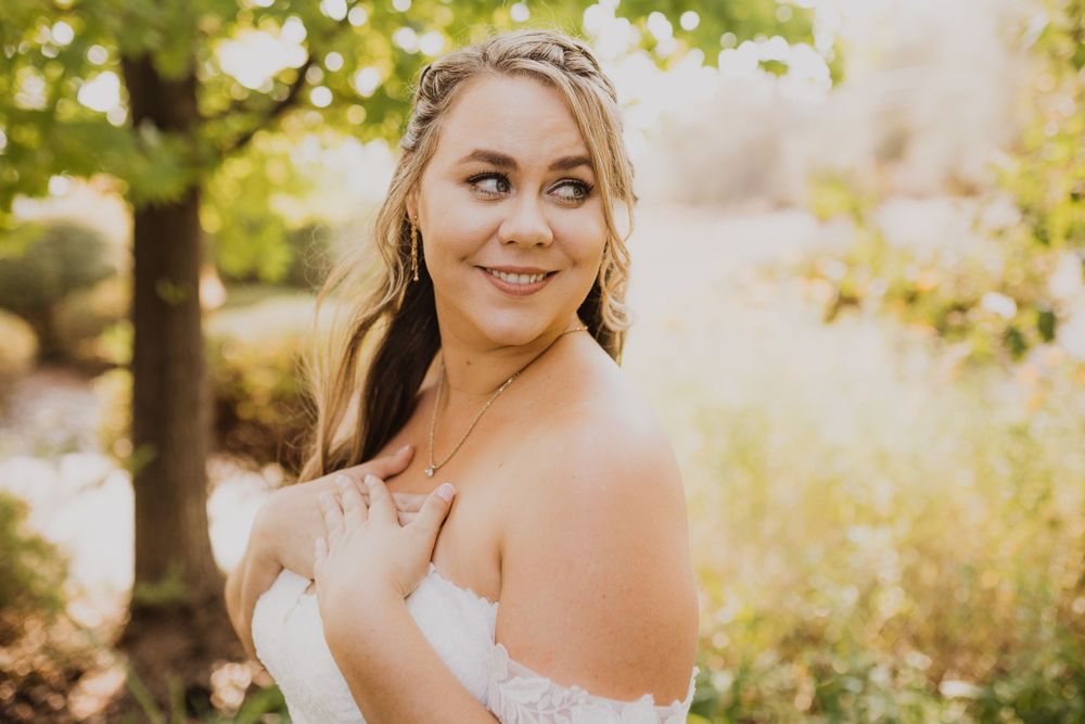 Bride in white lace dress poses in golden afternoon sunlight.