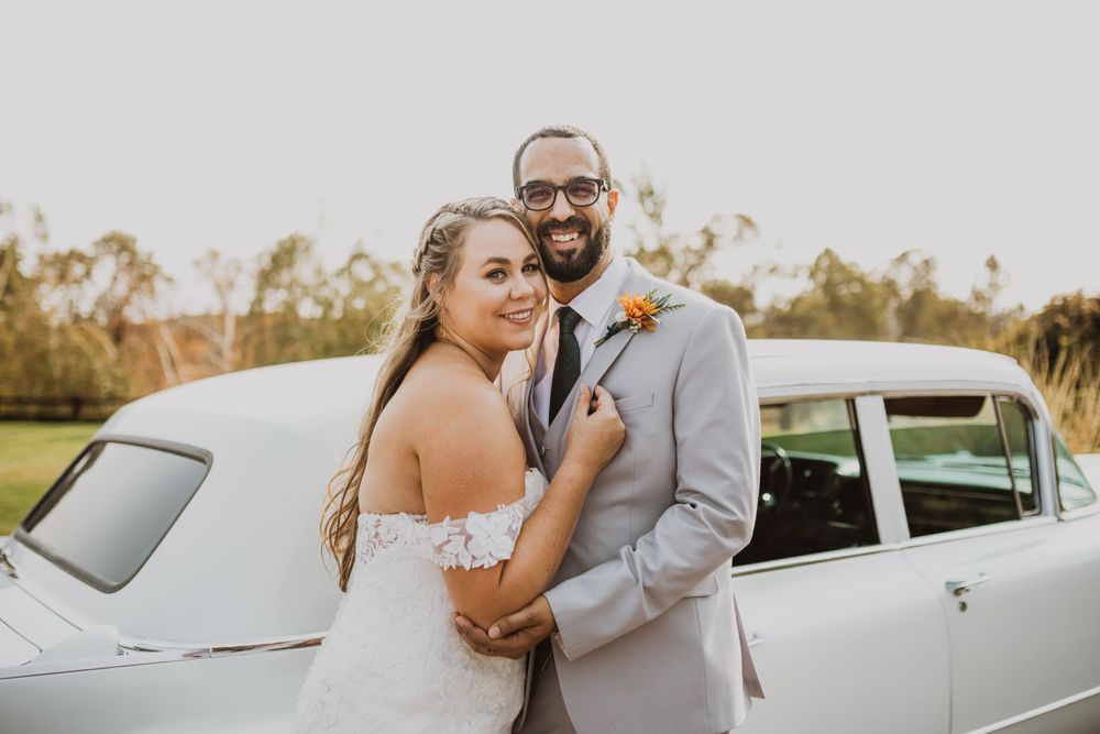 Classic white vintage limousine parked outdoors during sunset wedding photoshoot.