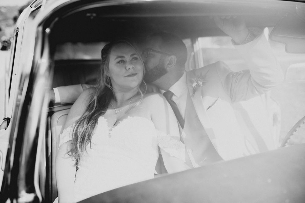 Black and white candid shot of wedding moments inside classic limousine.