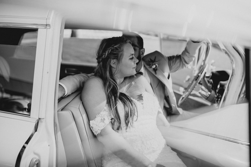 Black and white photo of wedding couple inside vintage limousine.