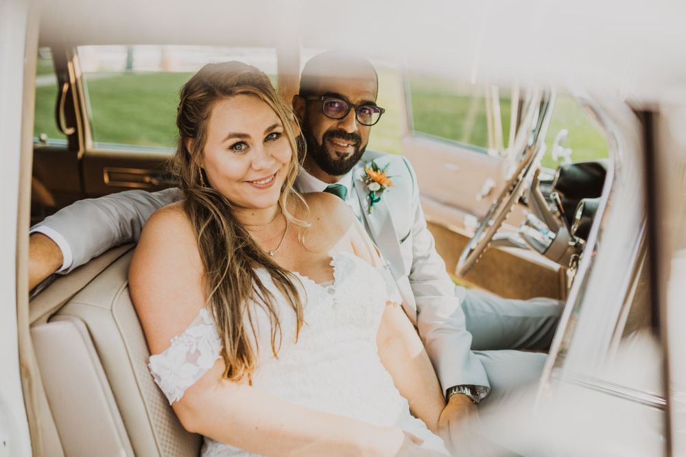 Candid wedding photo captured inside vintage limousine during daytime celebration.