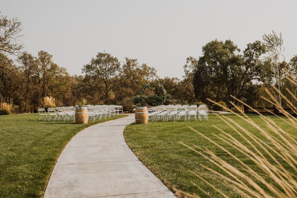 Outdoor wedding ceremony setup with white chairs and stone pathway.