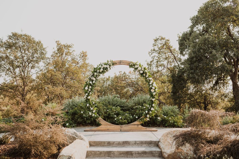 A rustic wedding venue exterior with wooden buildings and string lights against an autumn sky.