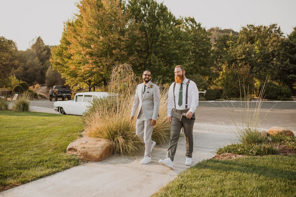 Couple walking along a paved pathway surrounded by autumn foliage and ornamental grasses.