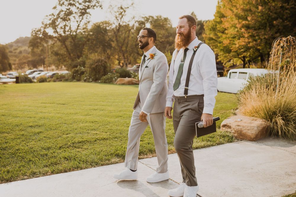 Wedding couple strolling on a concrete path with golden fall trees in the background.