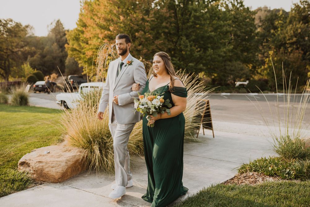 Couple in formal attire walking together on an outdoor path during golden hour.