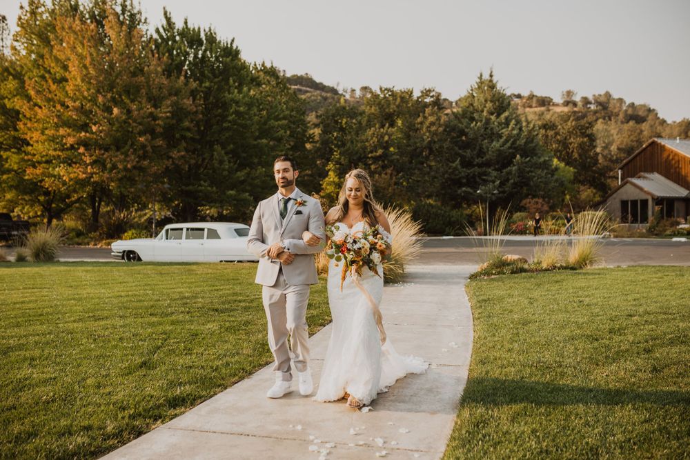 Outdoor wedding venue with white chairs arranged on a manicured lawn during golden hour.