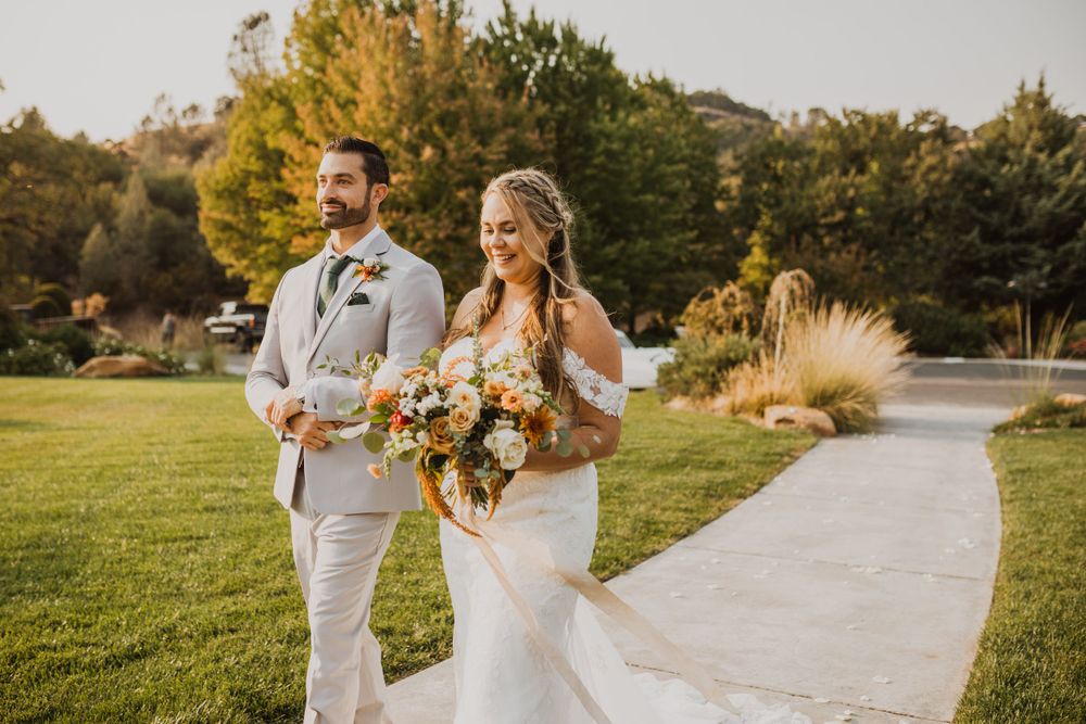 Wedding ceremony setup with white chairs and floral arrangements in an outdoor garden setting.