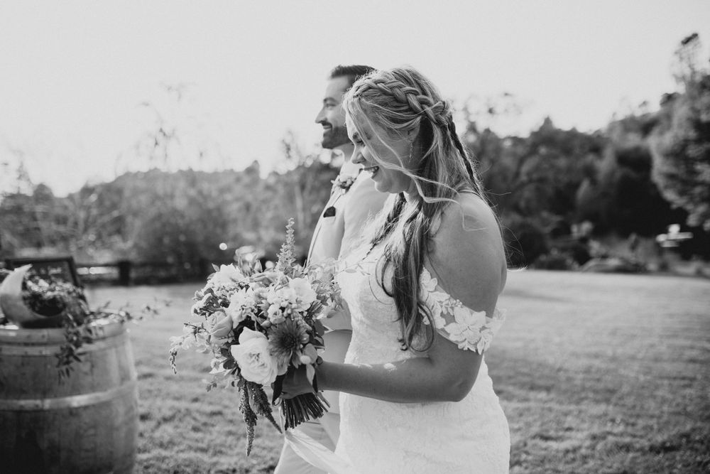 Black and white wedding photography capturing intimate moments in a natural outdoor setting.