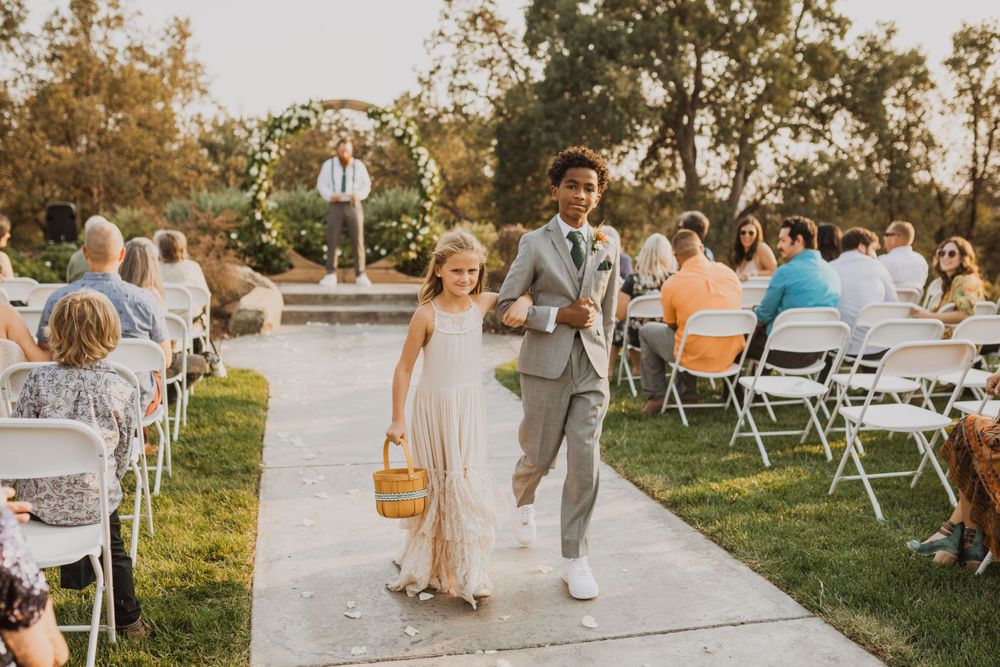 Wedding guests mingling on grass lawn with white chairs during outdoor celebration.