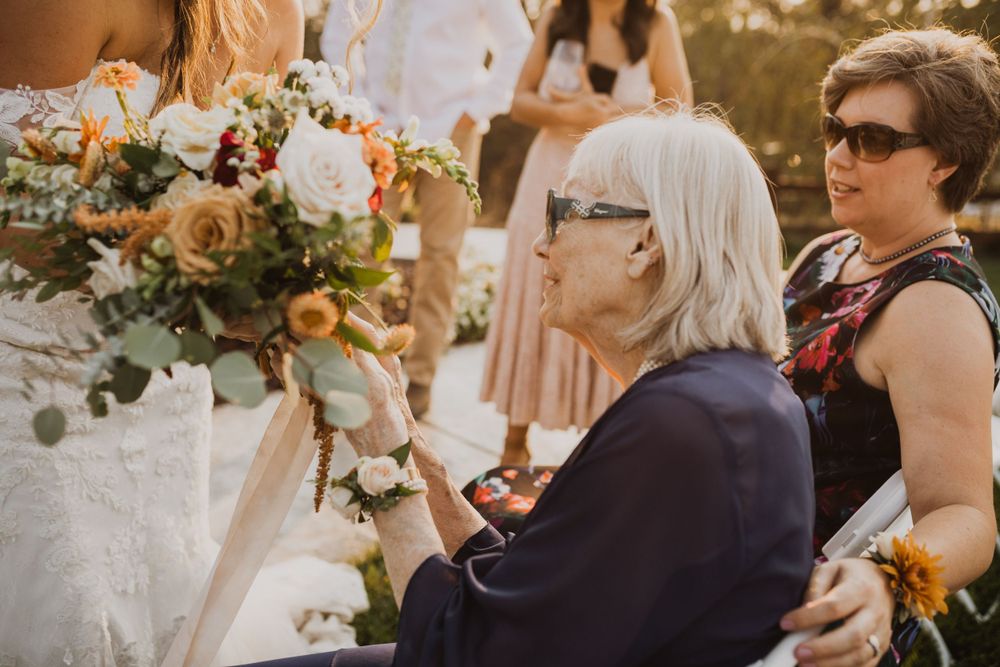 Wedding guests holding floral bouquets during outdoor celebration.