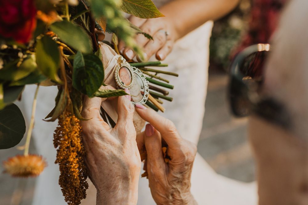 Detail shot of hands holding autumn-themed wedding bouquet with orange flowers.