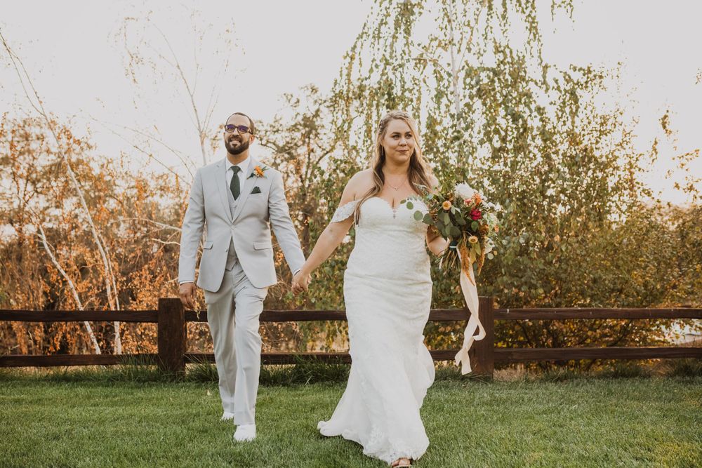 Wedding couple poses for portraits in a garden with willow trees during golden hour.
