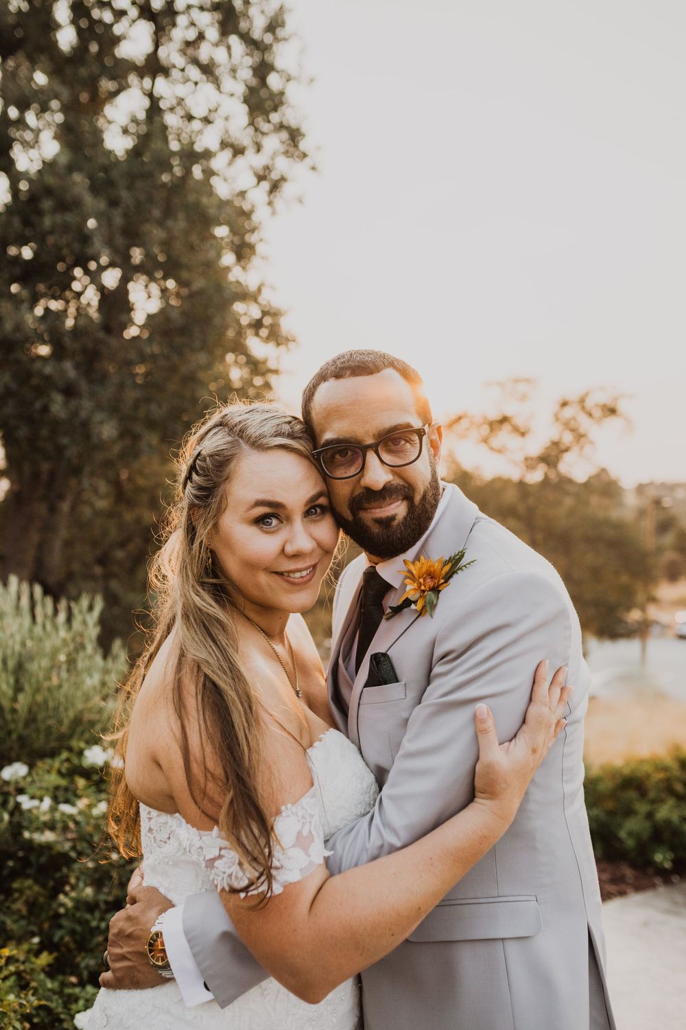 Joyful wedding couple embraces and laughs together during outdoor sunset photo session.
