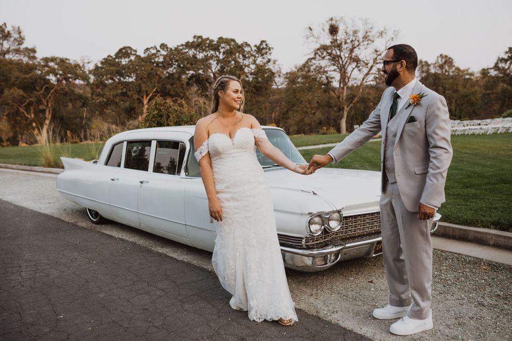 Newlyweds pose with vintage white car during their wedding photoshoot.