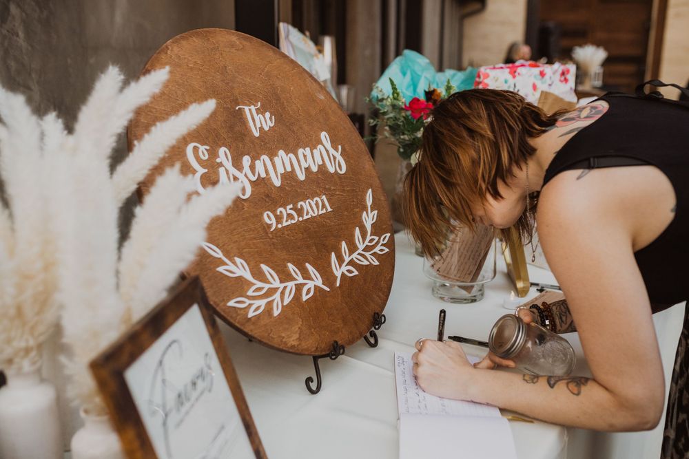 Wooden round sign with decorative text and floral design being signed at an event.