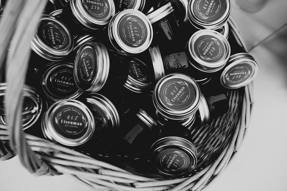Mason jars with metal lids arranged in a woven basket viewed from above in black and white.