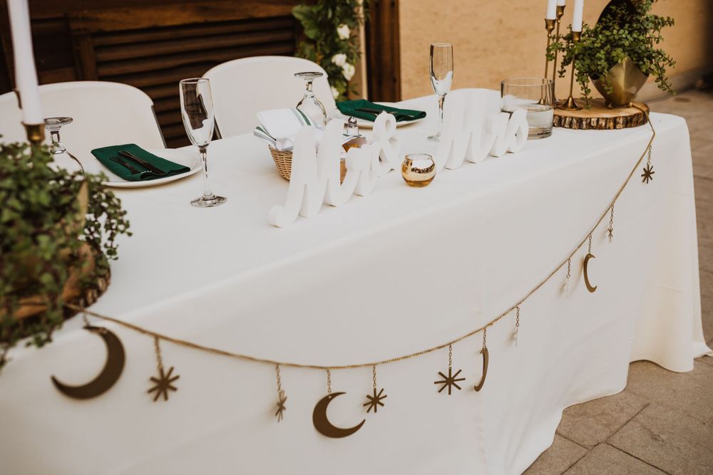 Wedding reception table decorated with celestial moon and star garland against rustic background.
