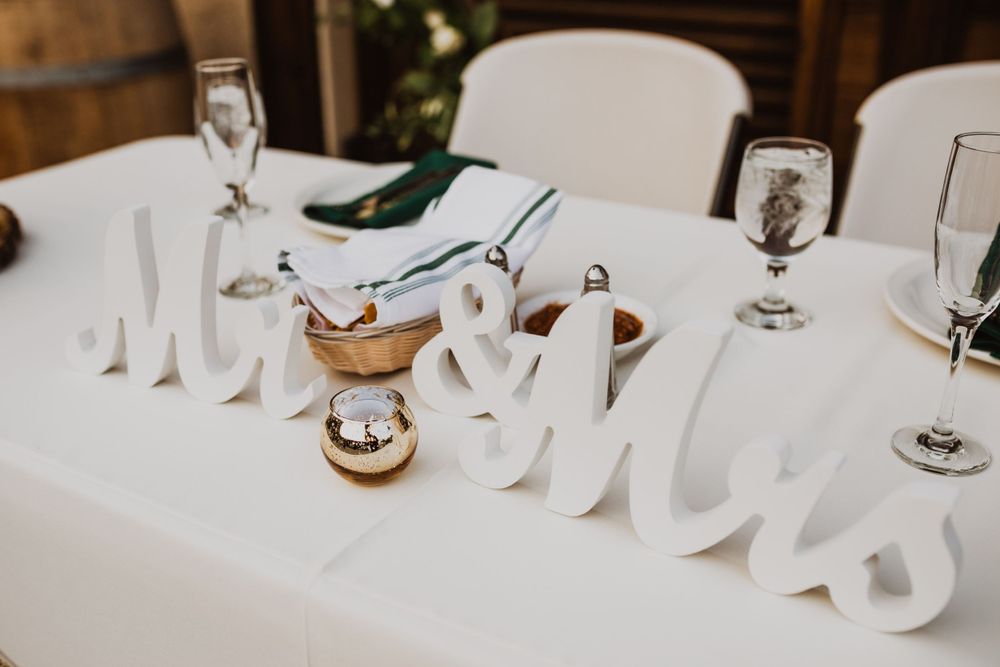 Wedding table setting with Mr and Mrs sign, wine glasses, and elegant place settings.