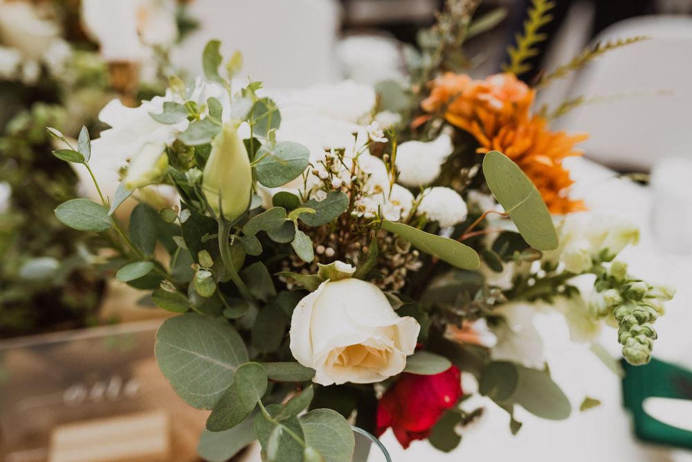 Close-up of wedding floral arrangement with white roses and orange accents.