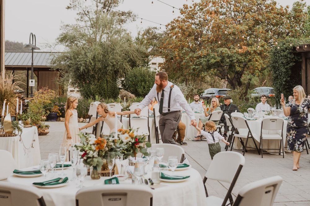 An elegant outdoor reception setup with decorated tables and floral centerpieces under string lights.