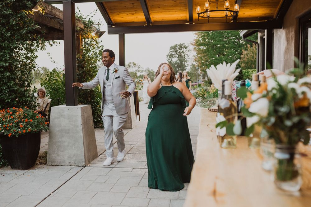 A joyful celebration moment at an outdoor wedding reception under warm lighting.