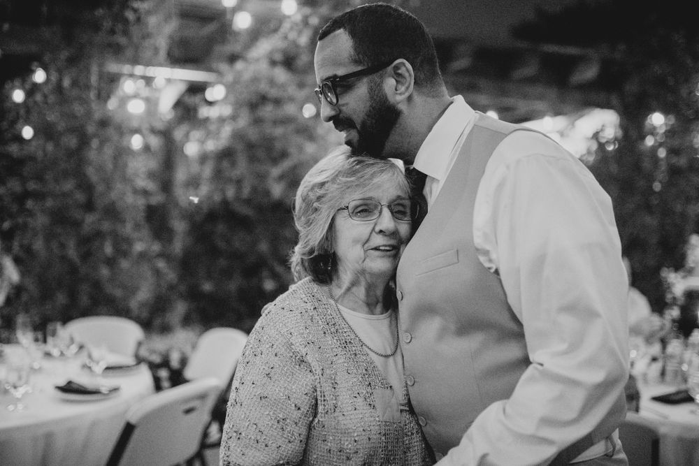 A tender black and white moment shared between guests during an outdoor evening reception.