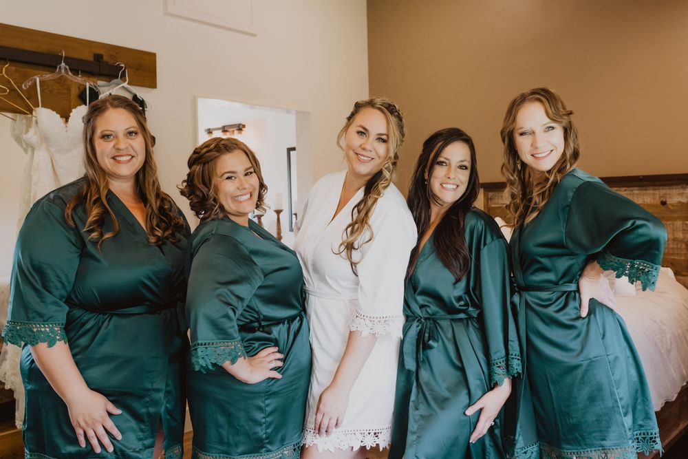 Bridesmaids in emerald satin robes celebrate during wedding preparations.