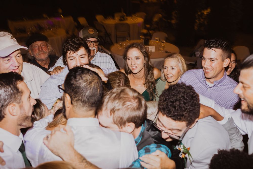 Crowded dance floor at a wedding reception with guests celebrating.