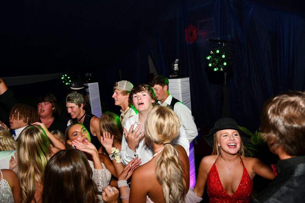 Energetic crowd dances and celebrates at a formal evening event under tent lighting.