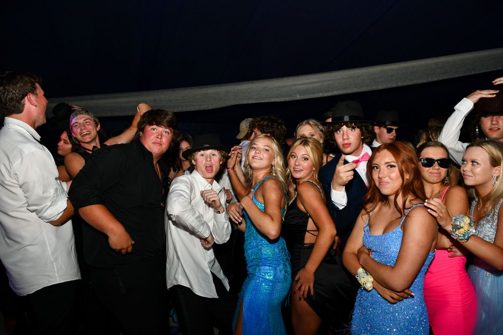Group of formally dressed attendees dancing and celebrating at a nighttime party.