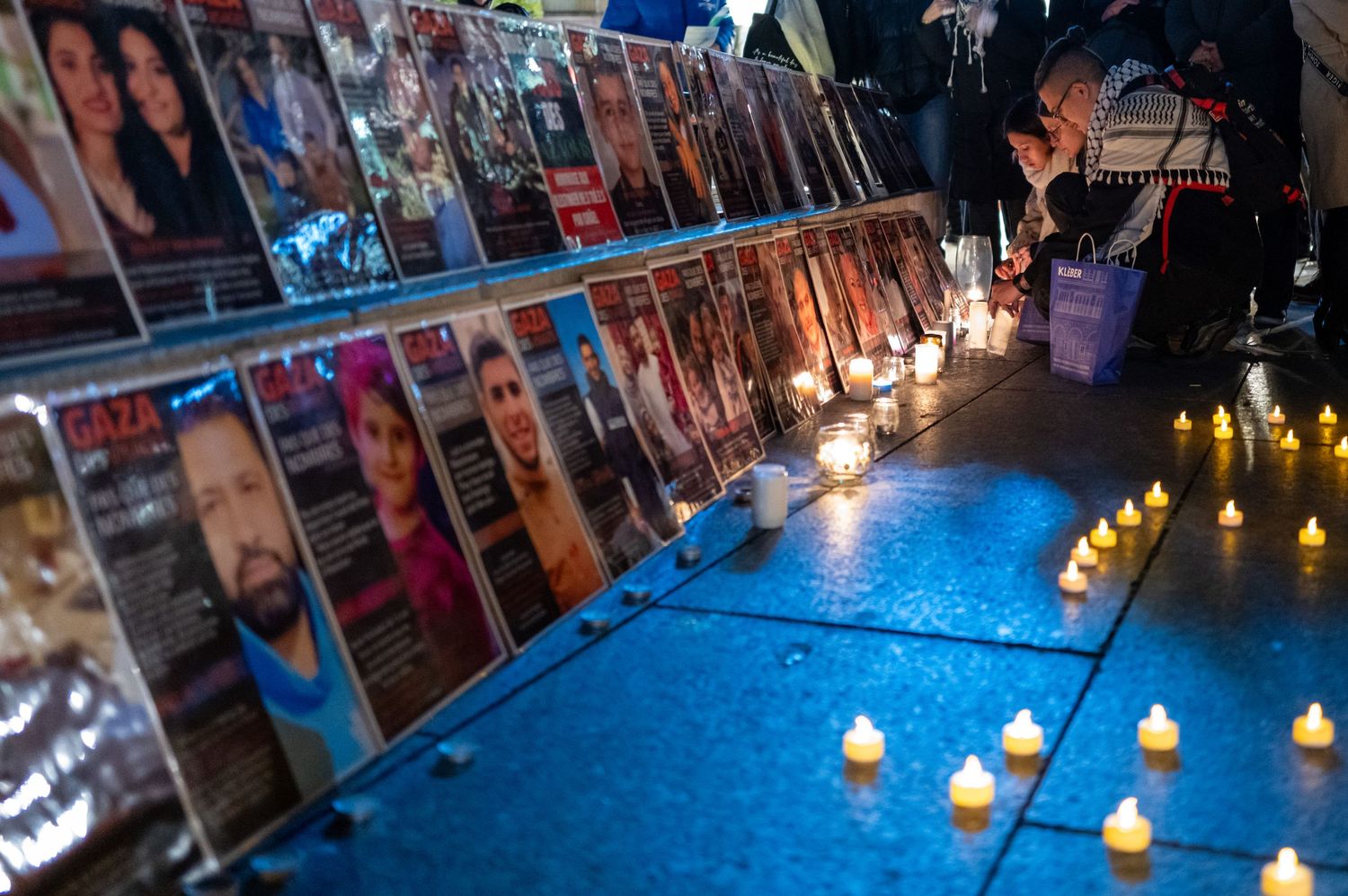 Memorial display with portraits, candles and flowers illuminated at night.