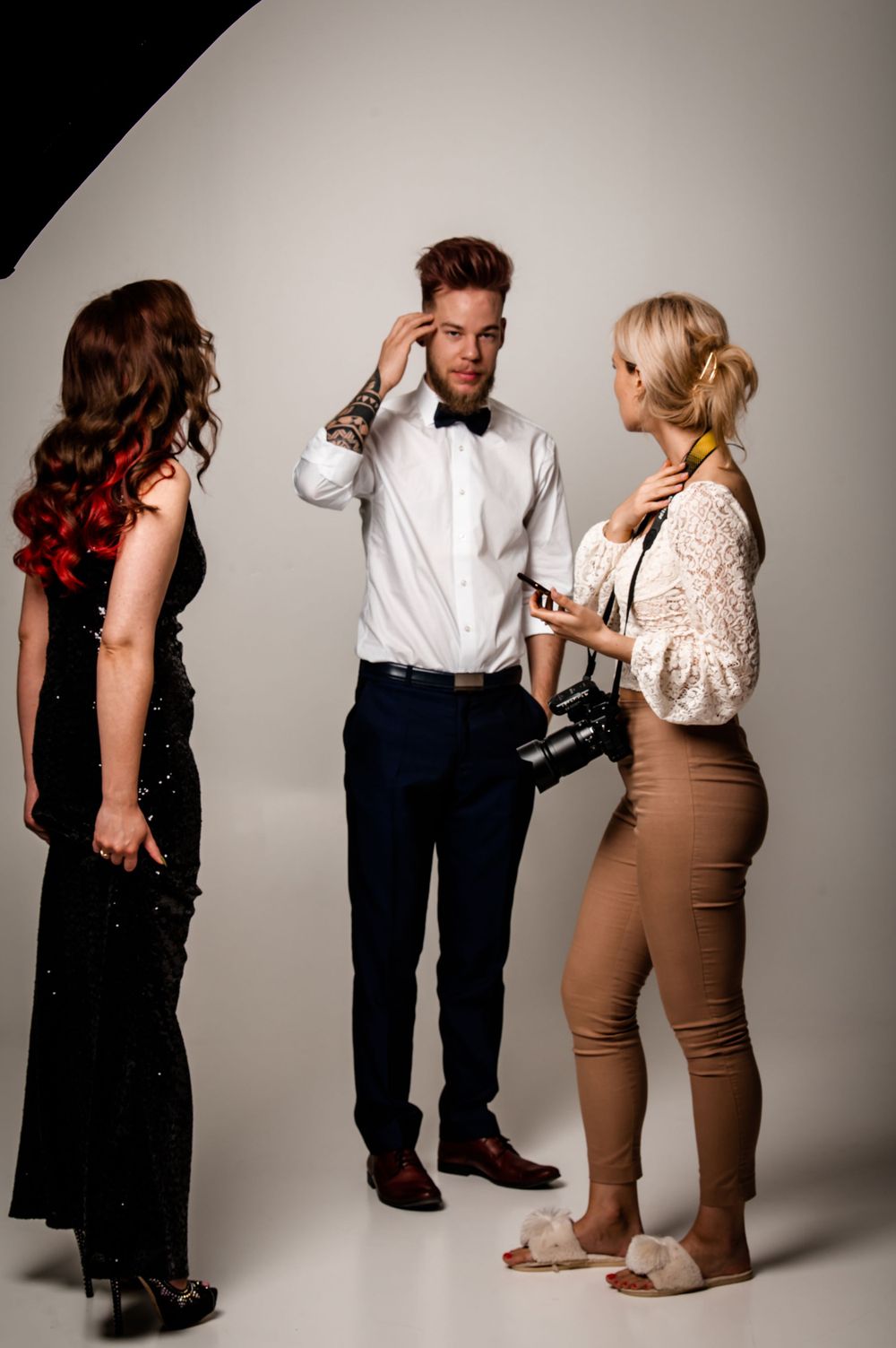 Behind the scenes studio photoshoot with models and stylist discussing poses and wardrobe.
