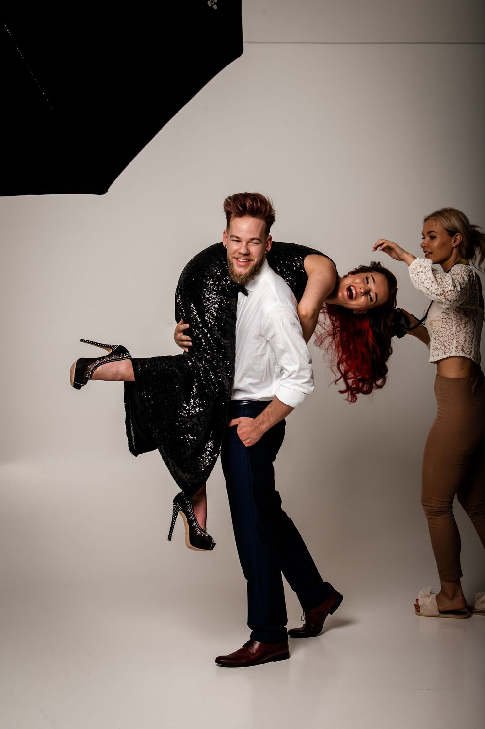 Dynamic studio photoshoot scene with dramatic poses and sequined formal wear.