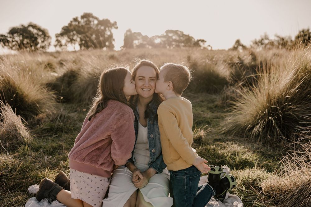 A heartwarming outdoor family moment shared on a grassy hillside during golden hour.