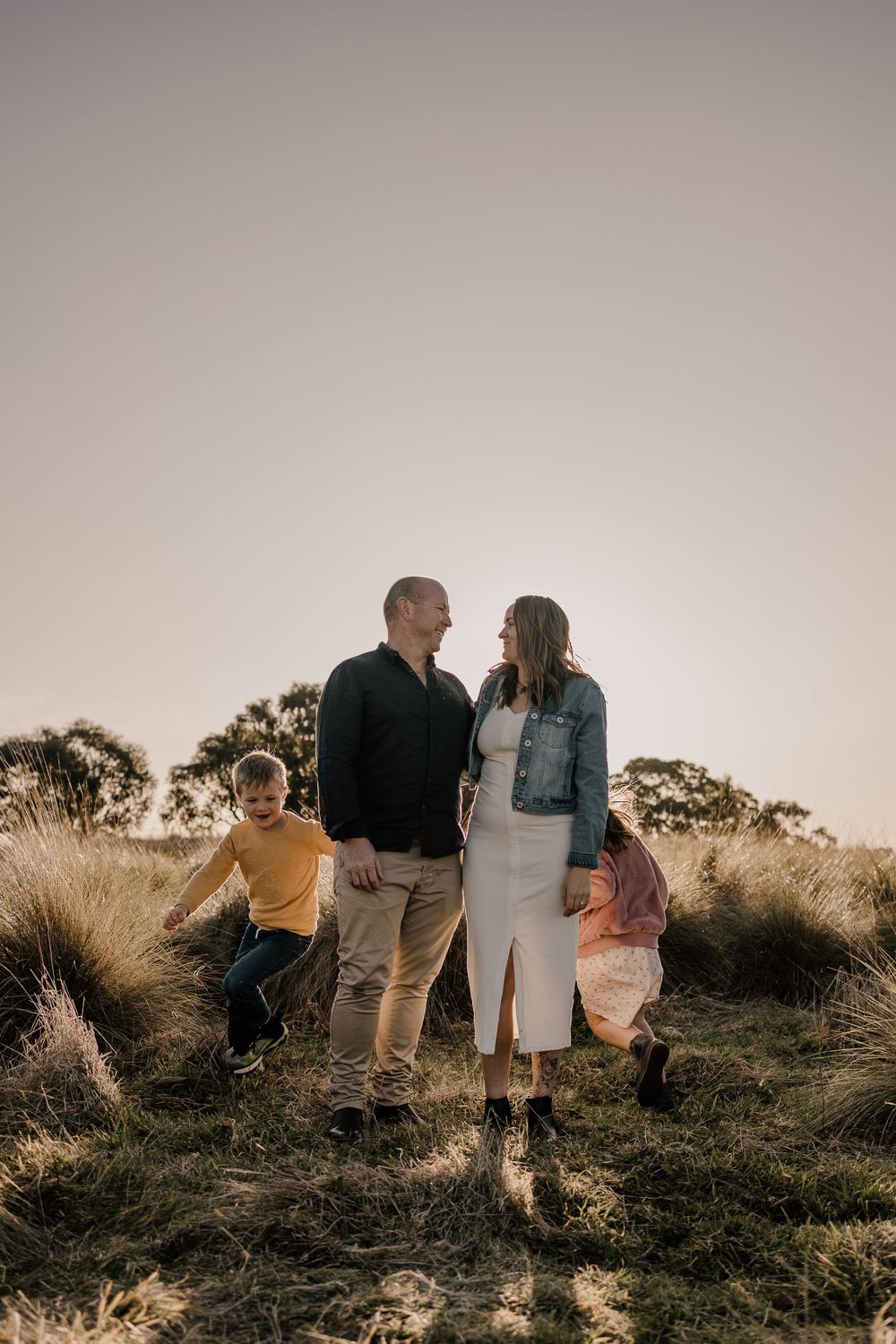 Family standing together in golden sunlight against a backdrop of tall grasses.