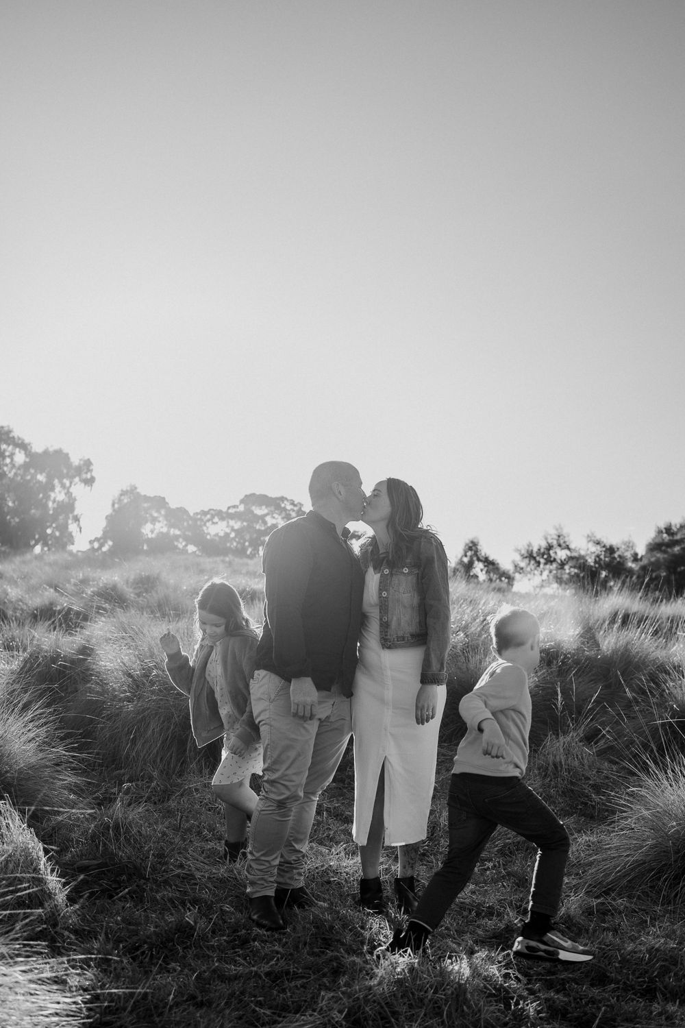 Black and white portrait of a family standing together among wild grasses.