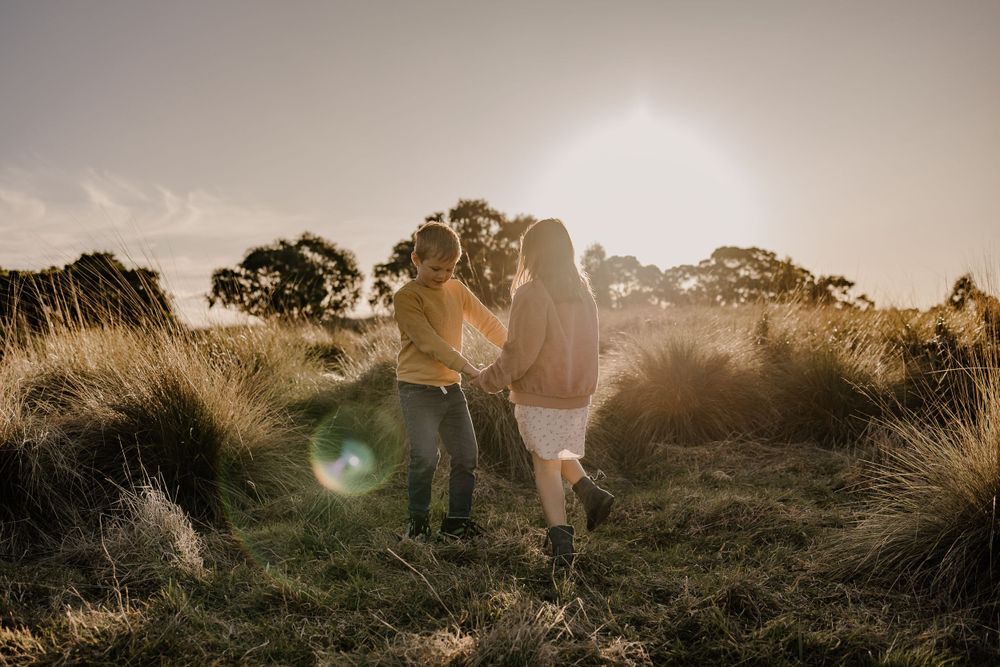 Romantic sunset silhouette of a couple embracing in a field of tall grass.