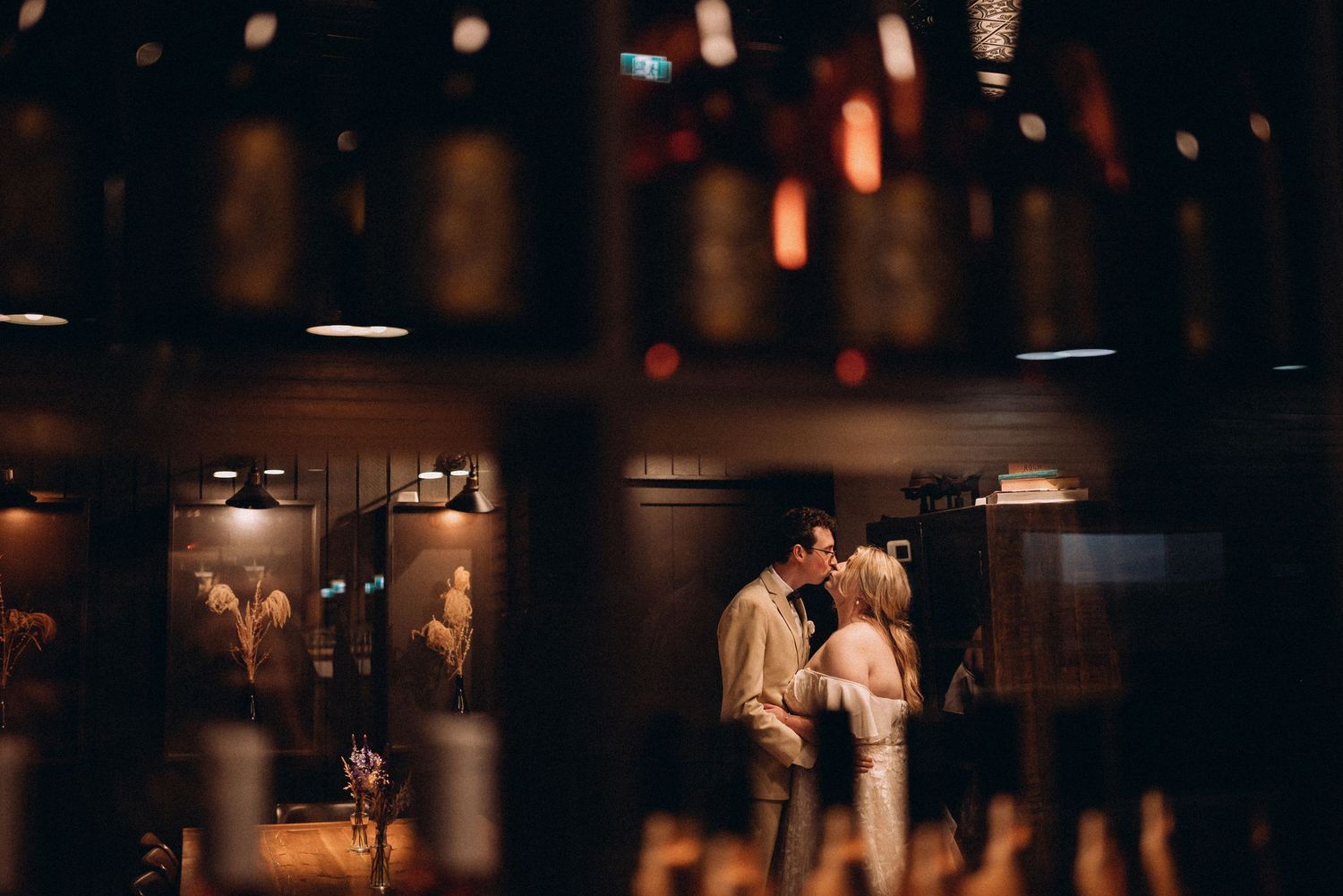 Romantic couple silhouetted against warm bokeh lights in an intimate indoor setting.