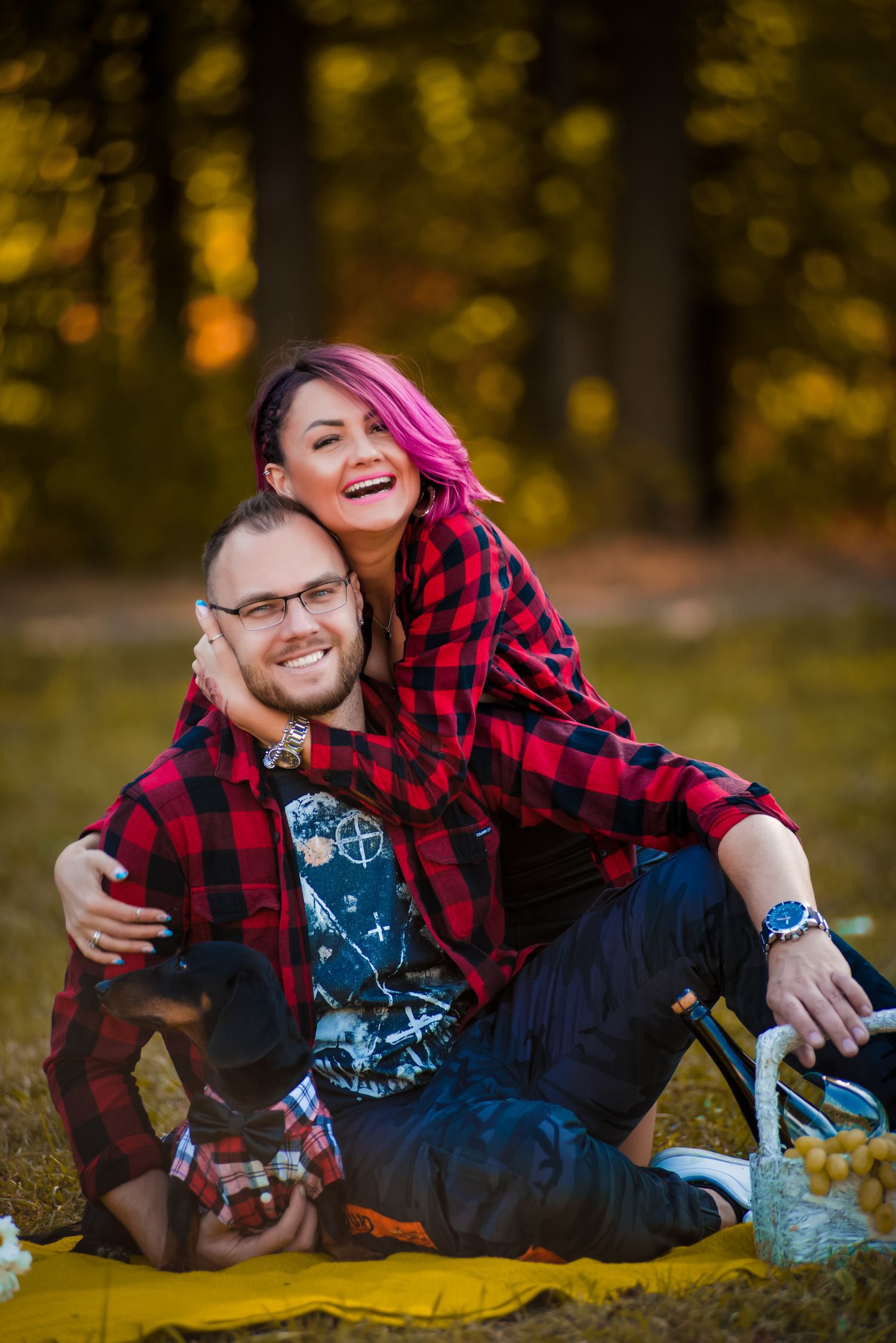 Couple in plaid shirts pose playfully on yellow blanket during autumn photoshoot.