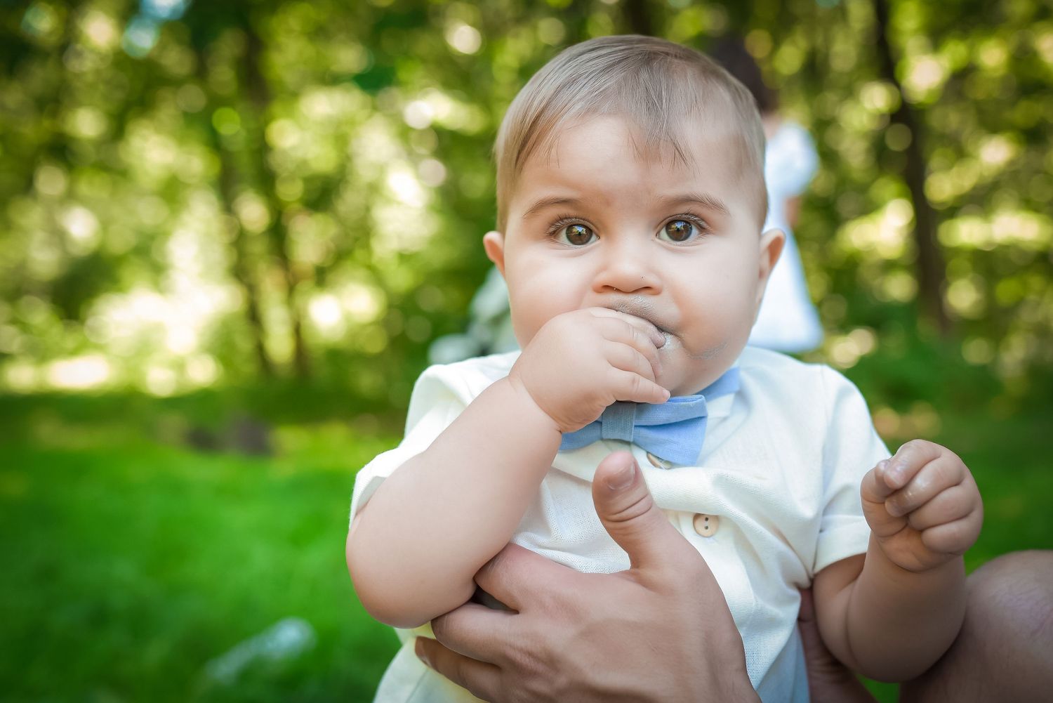 Close-up shots of baby in white outfit playing outdoors in garden setting.