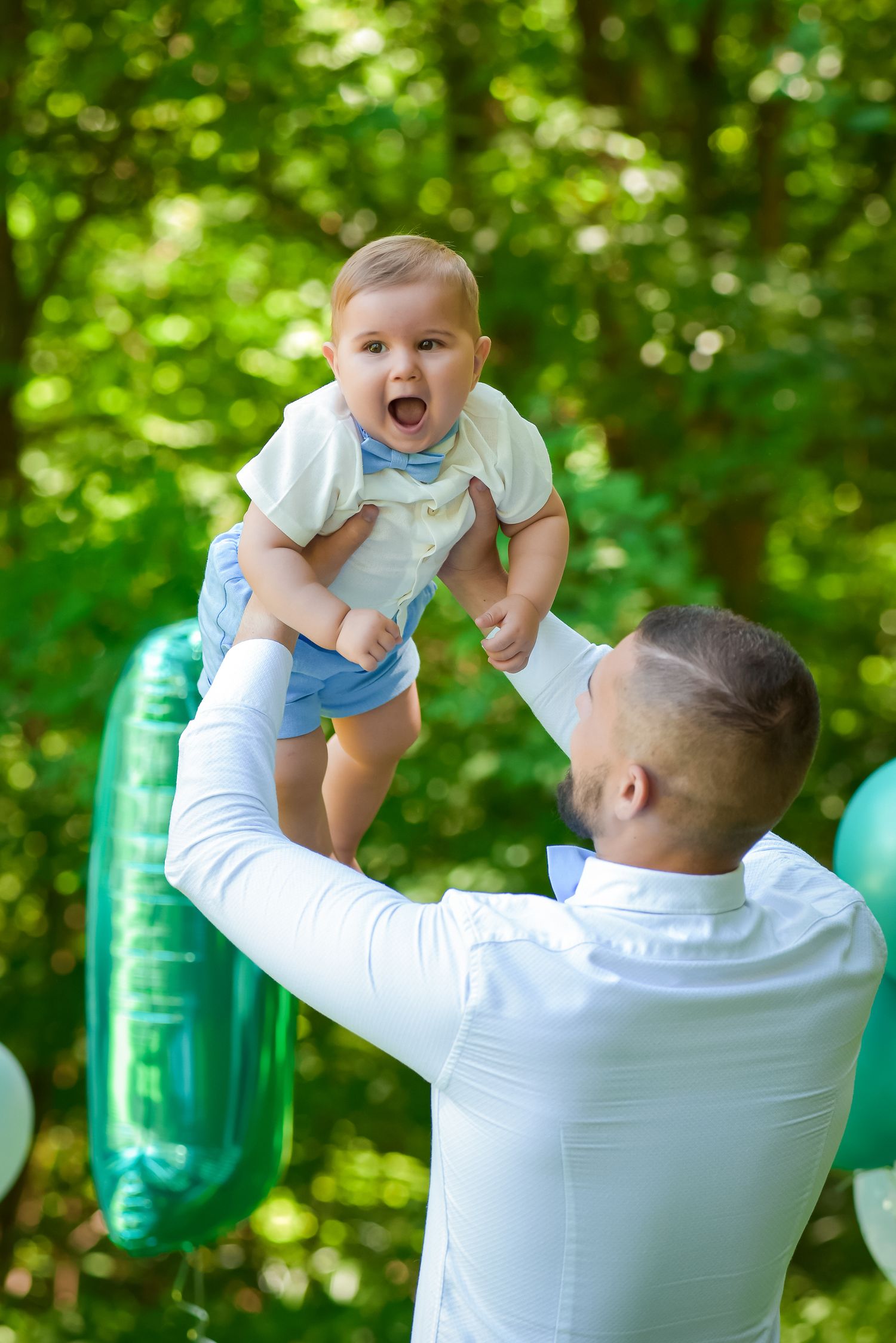 Joyful moments captured as baby is lifted high in the air during outdoor photoshoot.