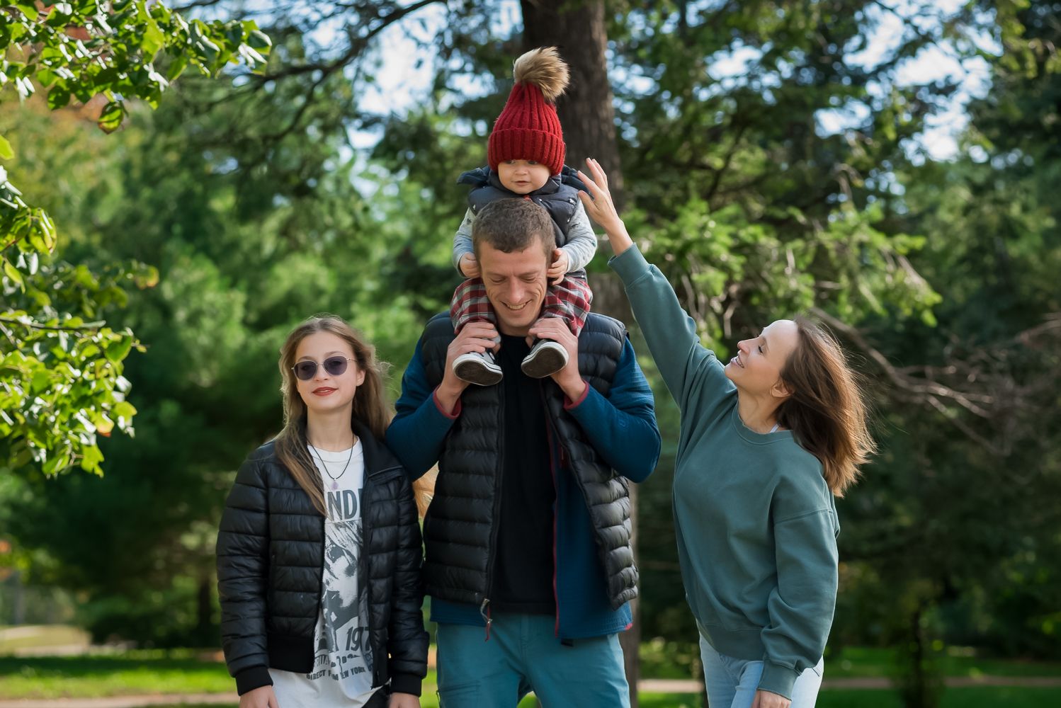 Family portrait session in a lush green park setting.