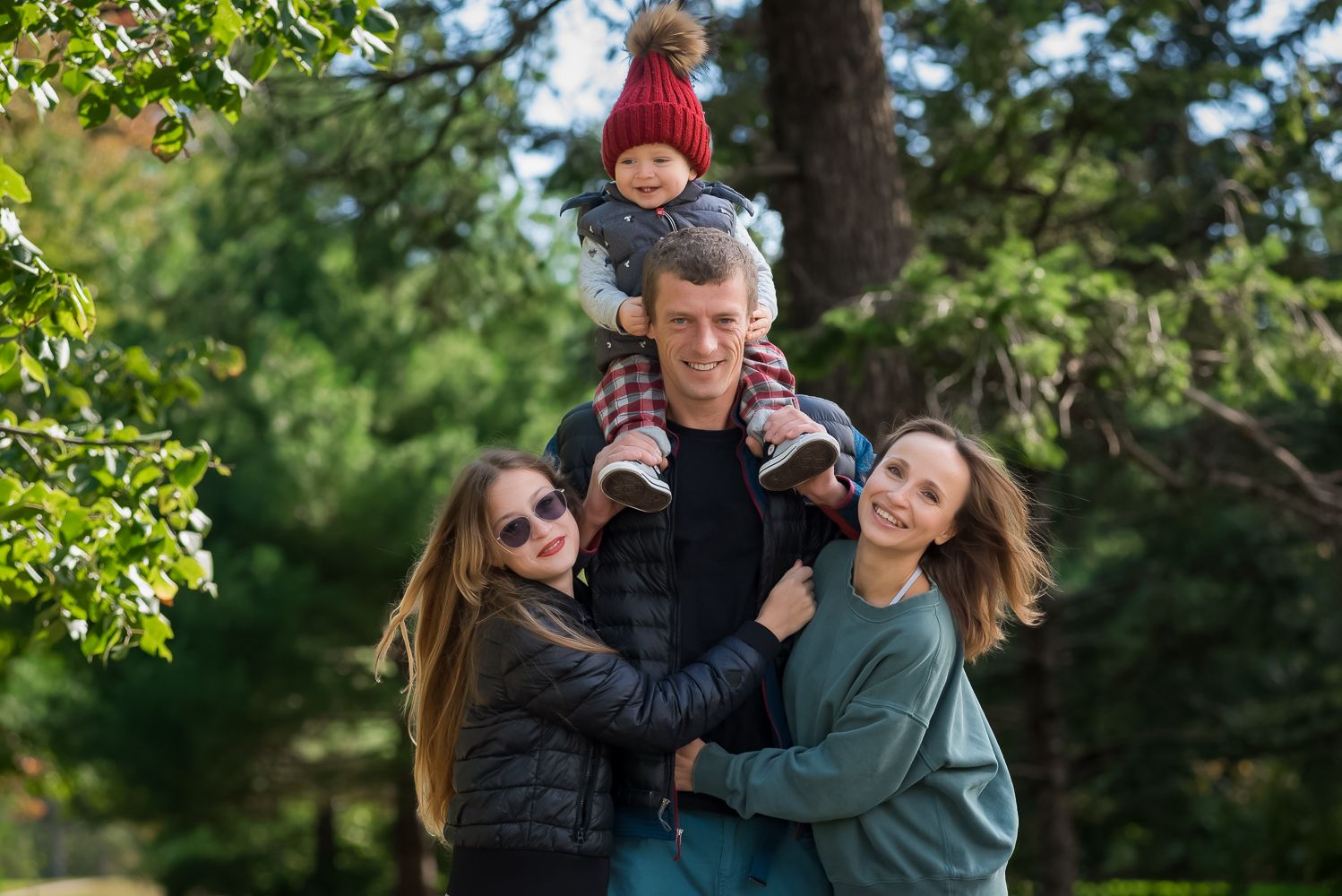 Happy family embracing outdoors in a green park setting.