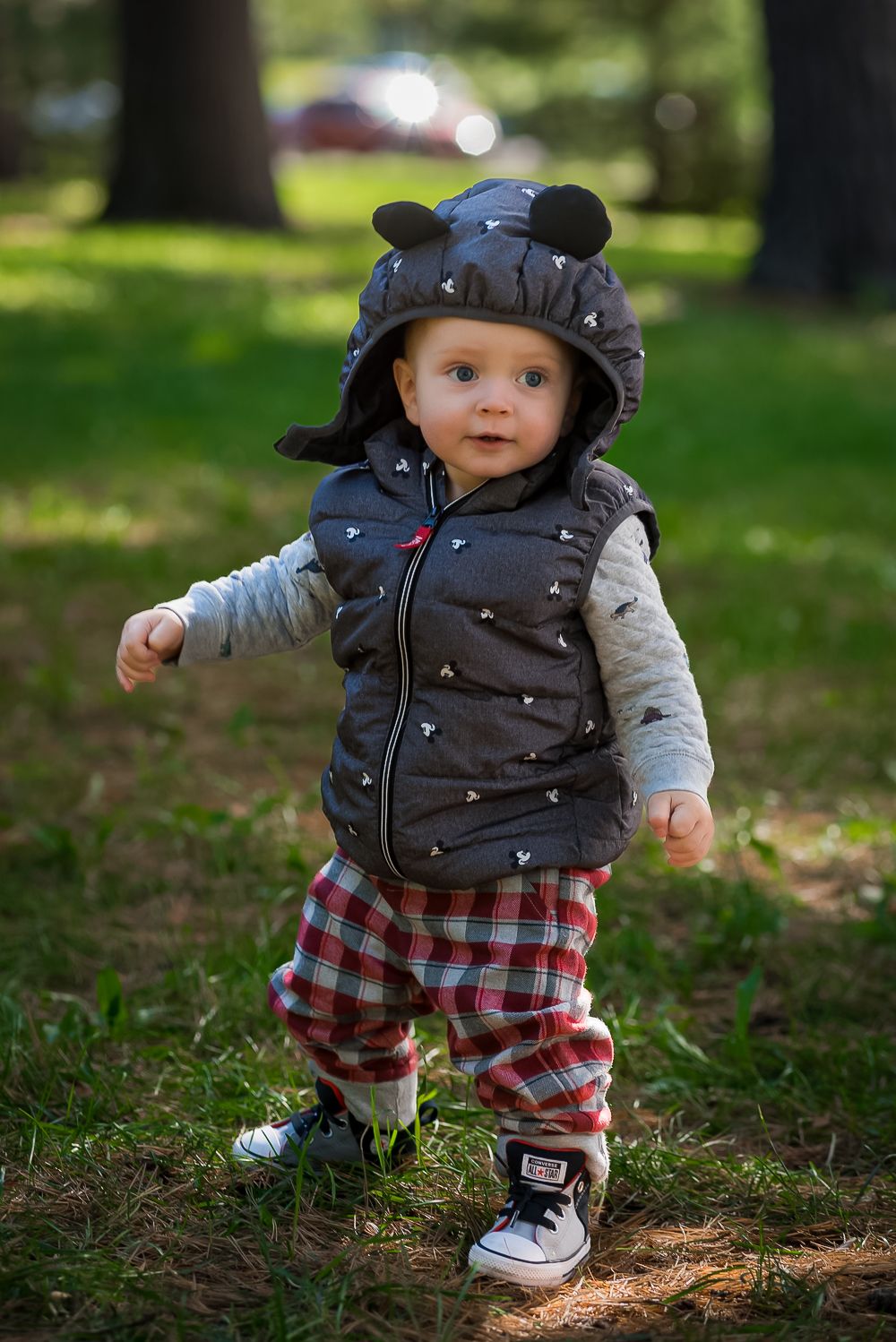 Small child in plaid pants and puffy vest exploring outdoors.